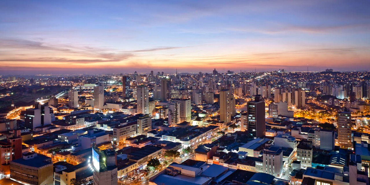 Imagem da cidade iluminada de Campinas ao pôr do sol
