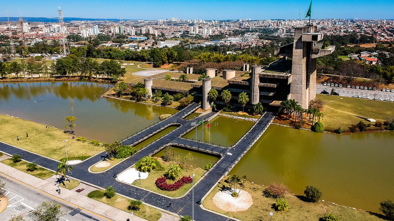 Imagem da cidade de Sorocaba, mostra uma vista aérea de uma estrutura moderna de ponte que se conectam, um lago e vegetações